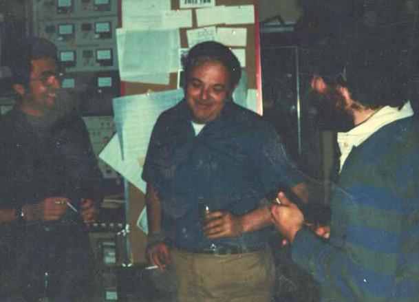 Three men holding beverages and smiling